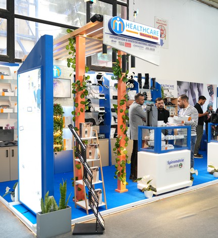 Stand d'exposant habillé de bleu et de bois, entouré de visiteurs